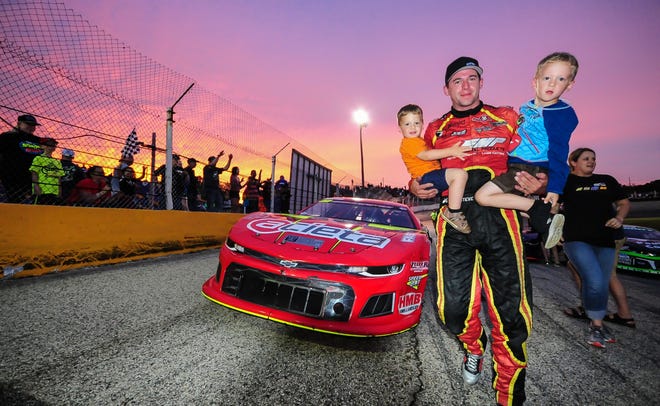 Stock car racer Steve Apel carries his sons, Harrison, left, and Cameron, after winning winning the a feature at Slinger Speedway in 2019.