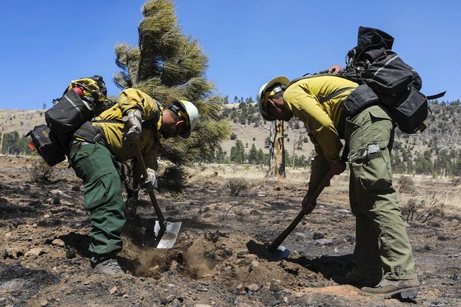 Two firefighters monitor hot spots from a wildfire burning on the outskirts of Flagstaff on April 21, 2022.
