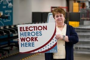 Utah County elections director Rozan Mitchell holds a "Election Heroes Work Here" sign during a tour of Utah County's elections equipment and review processes for administering secure elections Tuesday, April 19, 2022, in Provo, Utah. In Utah and other Republican-led states, unsubstantiated election fraud claims have upended support for vote by-mail, a practice that not long ago was overwhelmingly popular among Republicans. (AP Photo/Rick Bowmer)