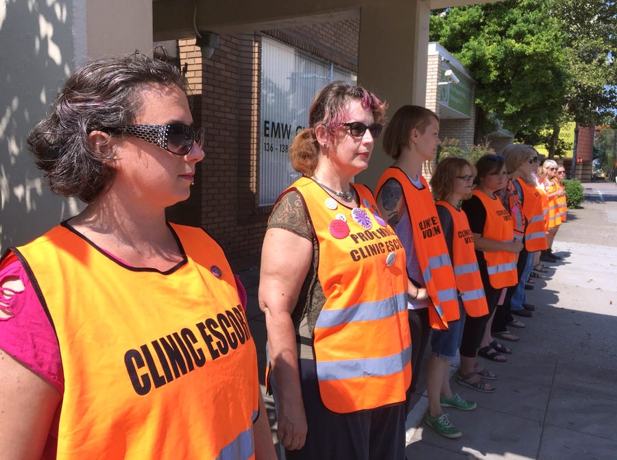 In this July 17, 2017, photo, escort volunteers line up outside the EMW Women's Surgical Center in Louisville, Kentucky.