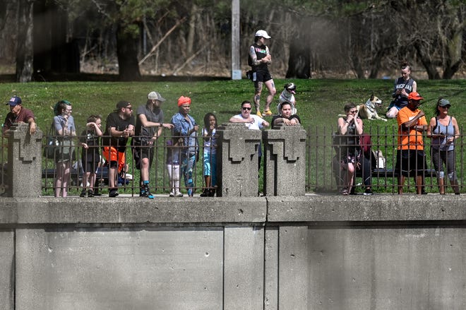 Onlookers stand near the Grand River as Lansing police and firefighters work to recover a body found in the water near the Brenke Fish Ladder on Saturday, April 23, 2022, in Lansing.