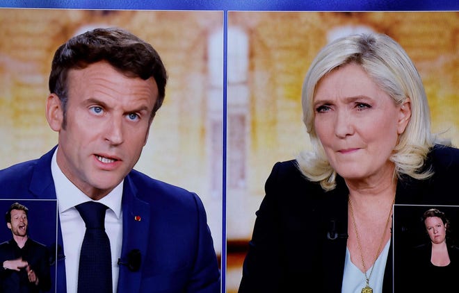 Screens displaying a televised debate between French President Emmanuel Macron and far-right presidential candidate Marine Le Pen in April 2022.
