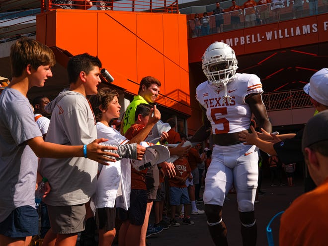 Texas defensive back D'Shawn Jamison slaps hands with fans as he takes the field for the annual Orange-White spring game at Royal-Memorial Stadium on Saturday.