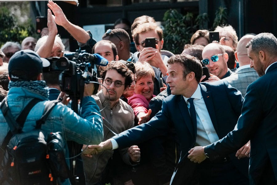 French President and centrist candidate Emmanuel Macron shakes hands with well-wishers as he heads to the polling station in Le Touquet, northern France, on April 24, 2022. France began voting in a presidential runoff election Sunday with repercussions for Europe's future, with centrist incumbent Emmanuel Macron the front-runner but fighting a tough challenge from far-right contender Marine Le Pen.