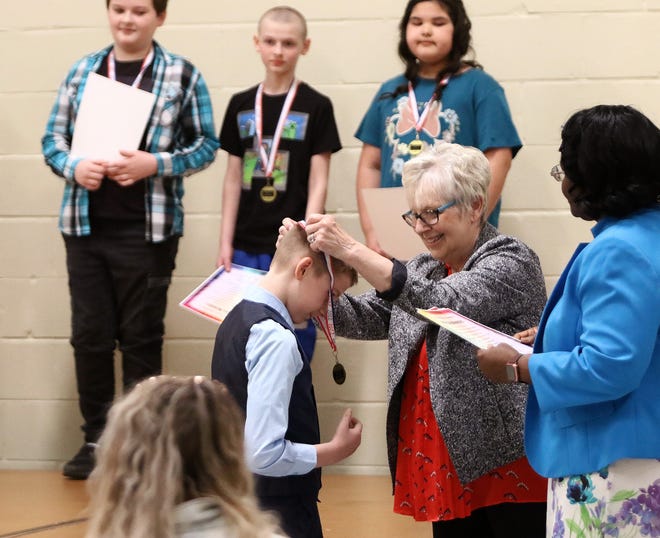Qutoa Club's Linda Kehres places a medal on Alliance Immediate School student DeAndre Spencer on Saturday, April 23, 2022, at the 2022 Alliance YWCA & Quota Sparkles Awards held in the gym at Regina Coeli.