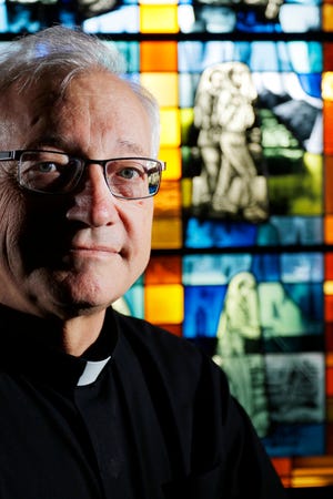 The Rev. Don Wolf poses for a picture at St. Eugene Catholic Church, a house of worship which features stained glass windows depicting images of the life and ministry of his cousin, Blessed Stanley Rother.