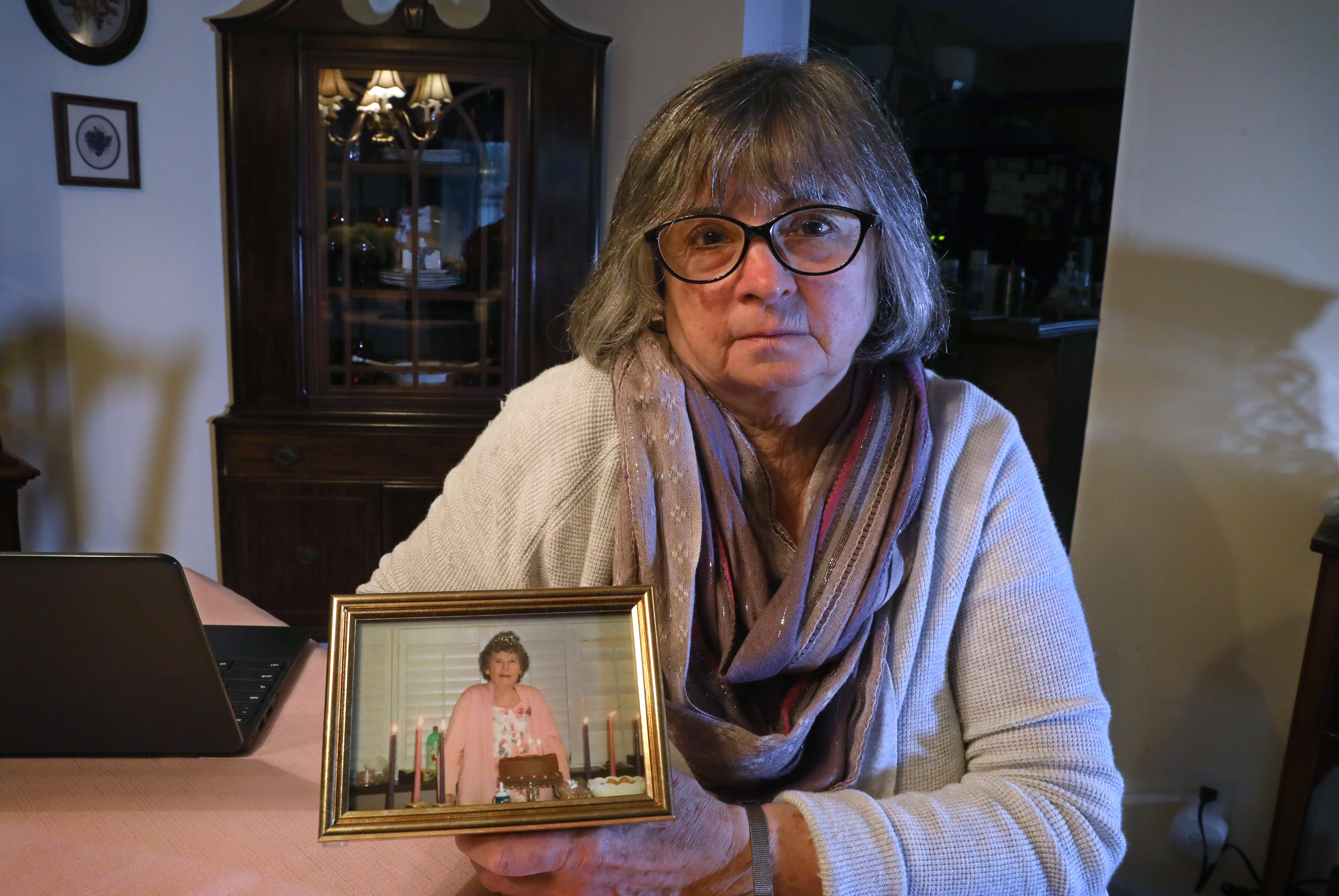 Jeannie Wells with a photo of her mother, Janet Deisenroth, at her home in Irondequoit Thursday, April 21, 2022. The photo was taken at Janet's 90th birthday party in April, 2018. She died Dec. 2, 2021 while a resident at The Hurlbut Nursing Home in Henrietta.