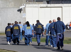 FILE - Inmates walk through the exercise yard at California State Prison Sacramento, near Folsom, Calif.