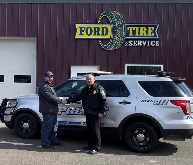 Newcomerstown Police Chief Gary Holland (right) is pictured with a representative of Ford Tire Service in Newcomerstown, which donated four new tires for a police vehicle.