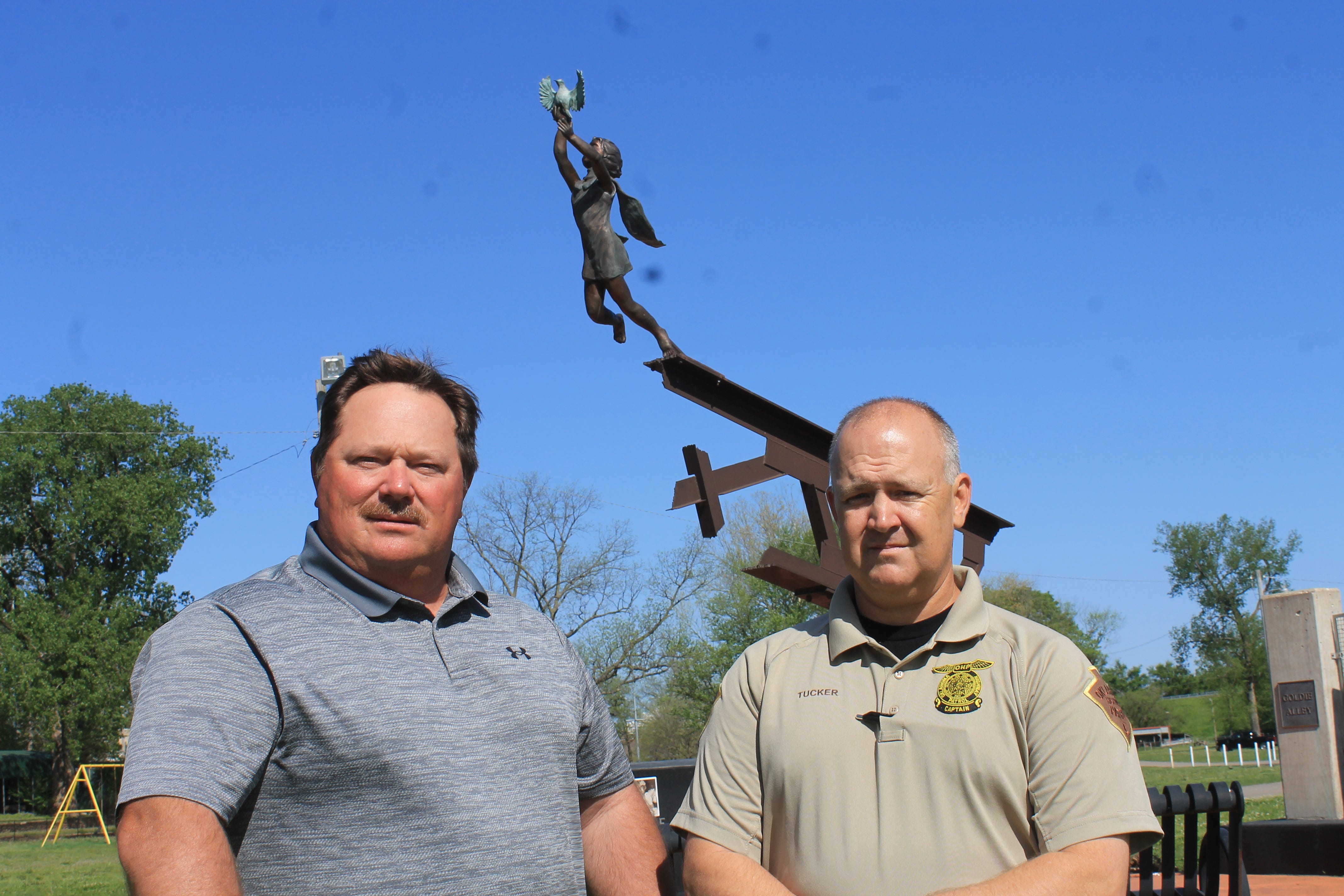 Rodney Copeland, retired Oklahoma Highway Patrol trooper, and Capt. Damon Tucker stand near the Webbers Falls Memorial Park sculpture built to remember those who died.