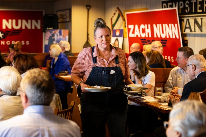A waitress clears plates as members of the Westside Conservative Club listen to a debate on Wednesday, April 27, 2022, at the Machine Shed in Urbandale, Iowa.