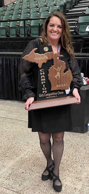 Richmond competitive cheer coach Kelli Matthes holds the Division 3 state championship trophy at DeltaPlex Arena in Grand Rapids on Saturday, March 5, 2022.