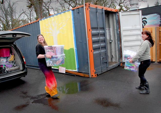 Ruth Patching, an Oregon Crafters Market member/vendor, moves some of her market sale items into a temporary storage area at the market, 215 N. Water St. in Silverton. At right is OCM manager Joy Ewing.