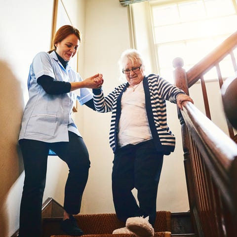 Young female caregiver helping senior woman walkin