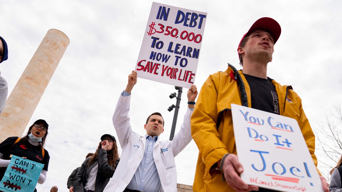 A person wearing a medical jacket holds a sign during a Cancel Student Debt rally outside the US Department of Education in Washington, DC, on April 4, 2022.