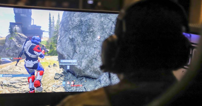 Le pilote joue le jeu "Halo infini" lors de l'inauguration du terrain de jeu ultramoderne de la base d'Eglin Air Forde.  Les jeux permettent aux aviateurs d'interagir entre eux et avec leur famille et leurs amis à la maison.