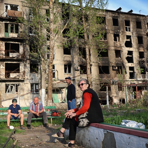 Local residents sit in the yard of their damaged b