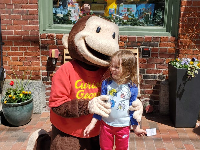 Curious George seems to be whispering a good joke to a delighted Isabella Ricciardi, 4, of Portsmouth. The beloved chimp was visiting Treehouse Toys as part of Children's Day festivities Sunday, May 1, 2022 in Portsmouth.