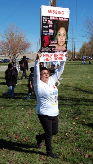 A participant in a walk and rally raising awareness about missing and murdered Indigenous people holds a sign on behalf of a missing woman on Nov. 13, 2021 in Berg Park in Farmington.