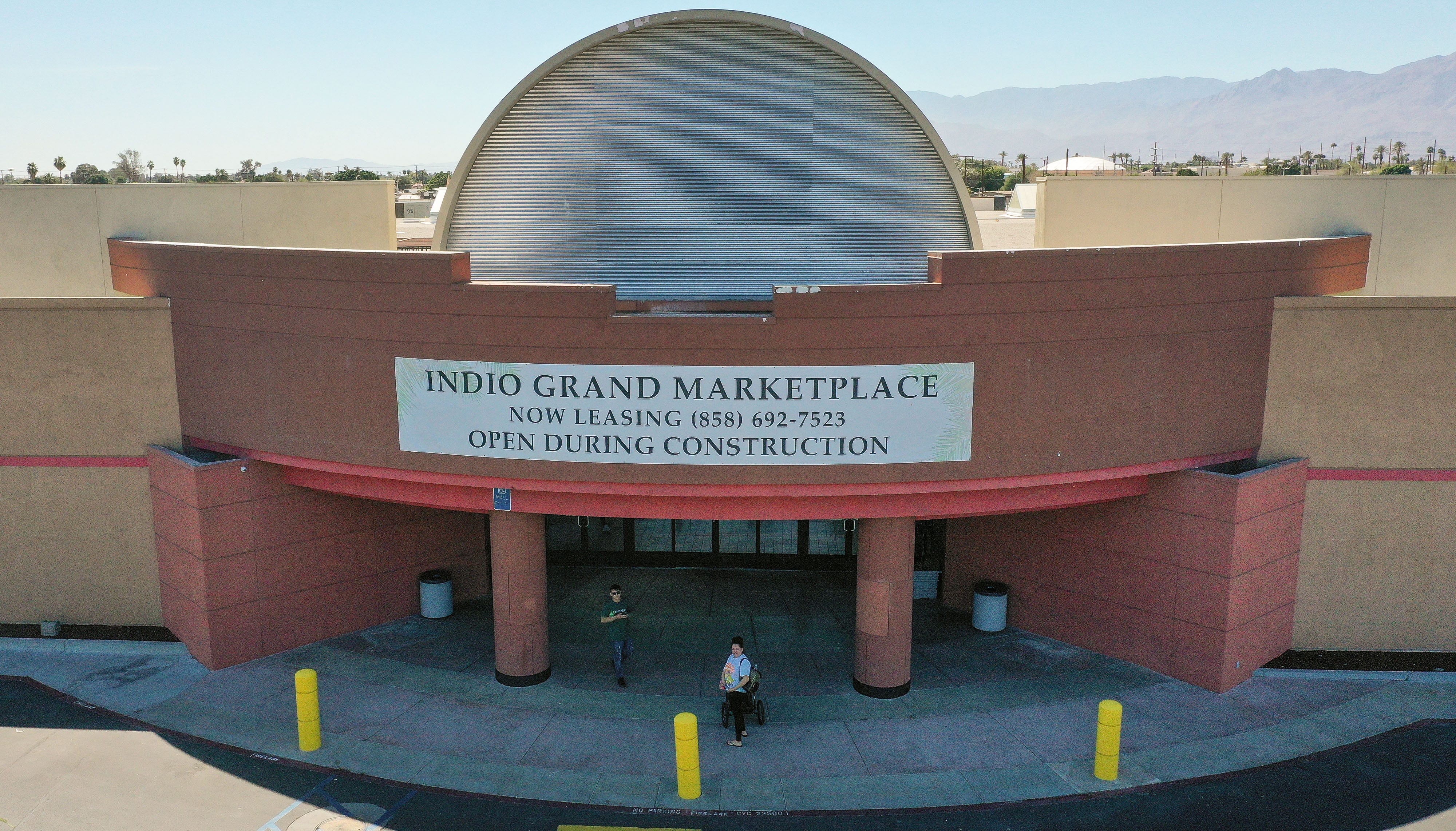 Shoppers come in and out of the main entrance to the Indio Grand Marketplace in Indio, Calif., March 24, 2022.
