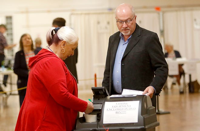 Tom Reed places his ballot in the machine while poll worker Judy Clark assists at the Mozelle Hall polling place Tuesday, May 3, 2022. TOM E. PUSKAR/TIMES-GAZETTE.COM