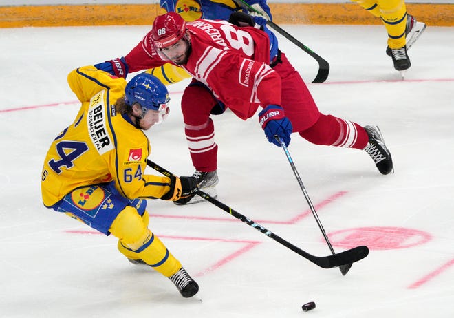 Russia's Kirill Marchenko, right, and Sweden's Jonathan Pudas battle for the puck during the Channel One Cup ice hockey match between Sweden and Russia in Moscow, Russia, Thursday, Dec. 16, 2021. (AP Photo/Pavel Golovkin)