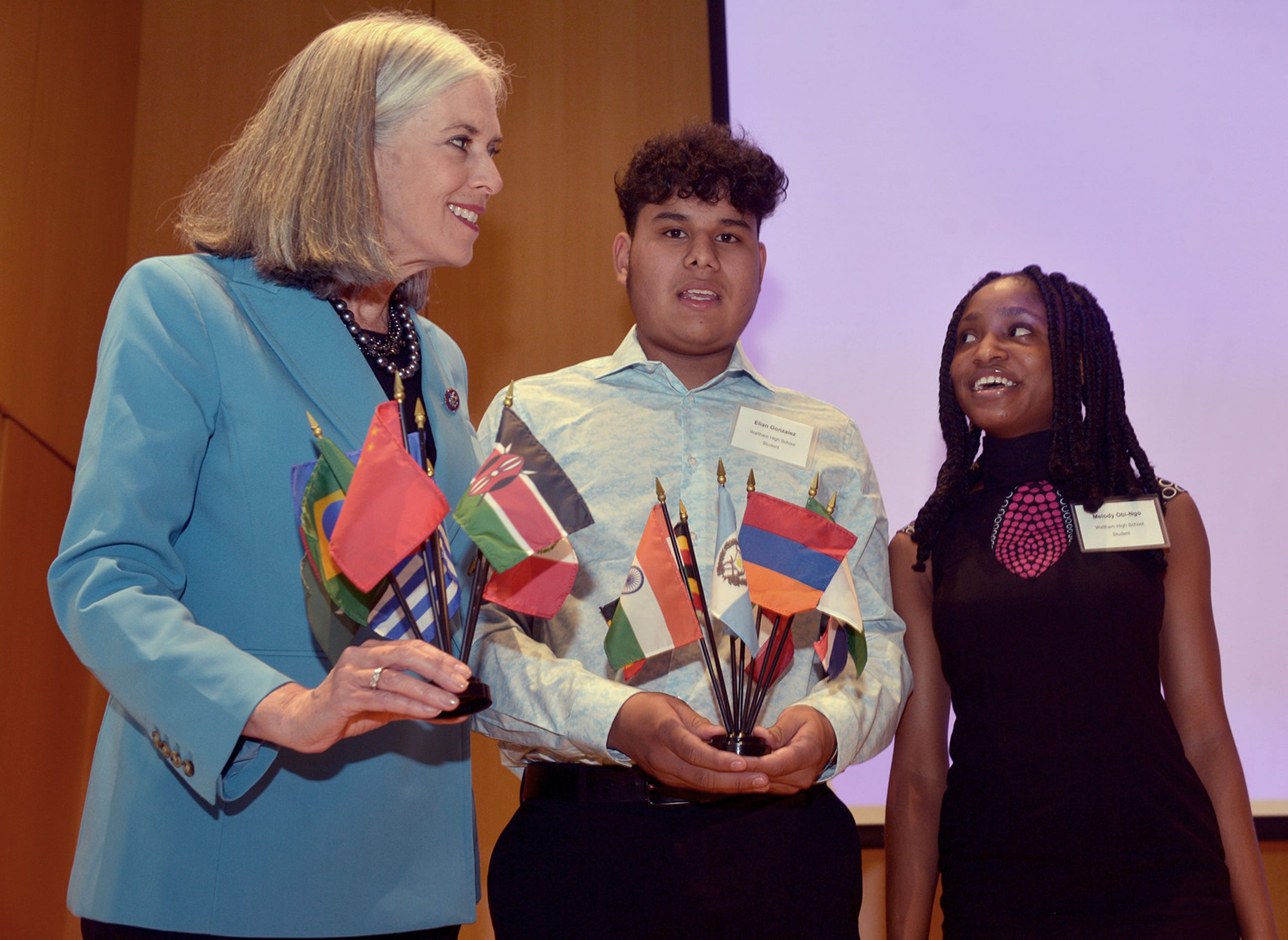After Rep. Katherine Clark, Assistant House Speaker, announced a $600,000 expansion of the MetroWest Scholars Early Start program, early college funding for Waltham students,  at Framingham State University, May 3, 2022, Waltham students Elian Gonzalez and Melody Obi-Ngo, Waltham posed with Rep. Clark and flags they gave her as a gift.