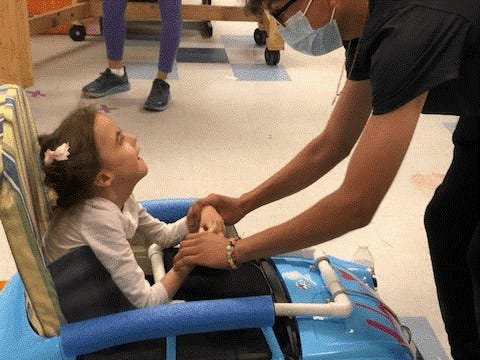 Juan Renteria, student at Lynn Community Middle School, holds hands with 8-year-old Hope Harrison in her new mobility car at Cruces Creatives in Las Cruces on Friday, April 8, 2022.