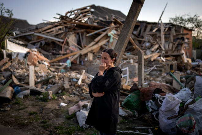 Anna Shevchenko, 35, stands next to the remains of her home in Irpin, near Kyiv, on Tuesday.  The house, built by Shevchenko's grandparents, was almost completely destroyed by bombing in late March during the Russian invasion of Ukraine.