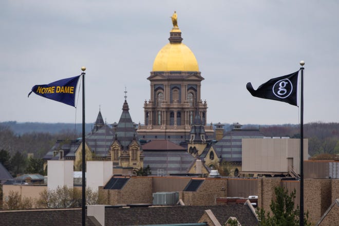 Οι σημαίες της Παναγίας των Παρισίων και του Γκαρθ Μπρουκς κυματίζουν καθώς ο χρυσός θόλος του κτιρίου διοίκησης φαίνεται στο βάθος την Παρασκευή στο στάδιο Notre Dame στο South Bend.