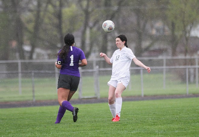 Sturgis' Brooke Troyer heads a ball toward a teammate, away from Bronson's Stephanie Marin in rainy soccer conditions against Bronson on Thursday.