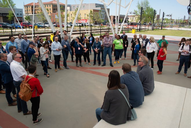 Intercity participants listen to Rogers city officials discuss Railyard Park under the shade of a newly constructed pavilion and concert stage.