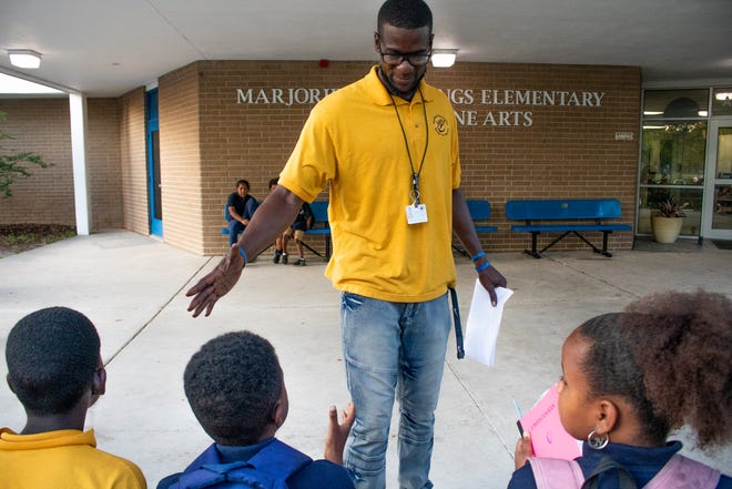 Chauncey Walker, founder of Develop A Dream and a Physical Education teacher at Marjorie Rawlings Elementary, shakes the hand of a student at the school during the father cheering event organized by the Fatherhood Initiative of Gainesville For All in Gainesville on May 5, 2022. Walker worked with GNV4all with Jacob Lawrence to help coordinate the event to help encourage students and bring positive role models to support them.  (Lawren Simmons/Special to the Sun)
