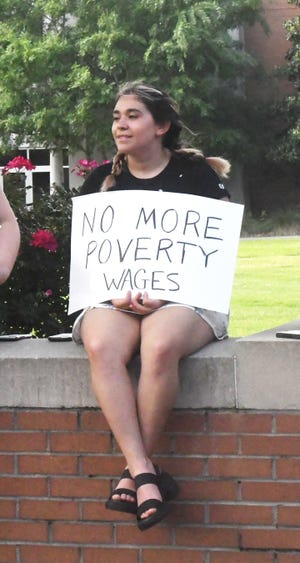 Isabel Loya, a graduate teaching assistant at the University of Southern Mississippi, holds a sign during a rally on campus for higher wages for university staff Thursday, May 5, 2022, in Hattiesburg, Miss.