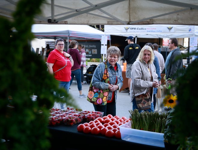 Shoppers walk past the StoryBook Orchard stand during the opening day of the 2022 downtown Farmers' Market in Des Moines on Saturday, May 7.
