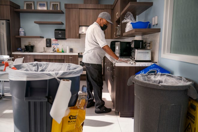 Stockton Maintenance Group janitor Jean Pierre-Louis, 73, cleans a break room kitchen at the Palm Beach County Water Utilities Dept. Customer Care Center in Boynton Beach, Florida on May 6, 2022. 