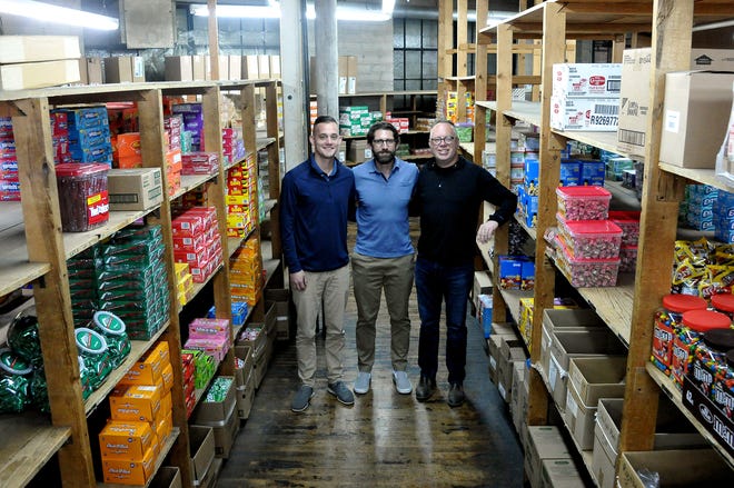 Friendly Wholesale owner Austin MIller, General Manager Jeremy Menegay and owner Matt Plocki amidst candy racks and other items that customers can buy on the shelves.