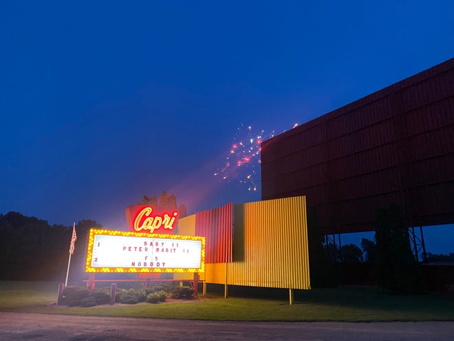 Fireworks are seen in the background with a marquee sign lit at night at the Capri Drive-In Theater in Coldwater.