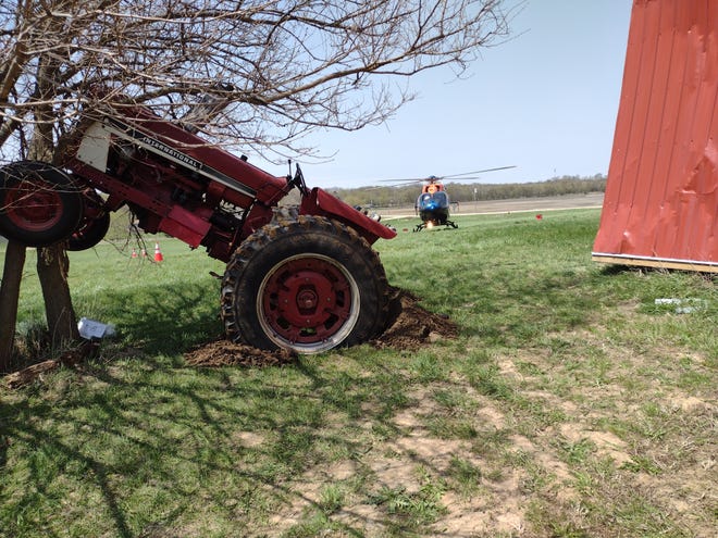 A Flight for Life helicopter waits to transport a Dodge County man from the scene after he was run over by a tractor he was repairing. After injuring the man, the tractor drove through the wall of a machine shed and came to rest against a tree.
