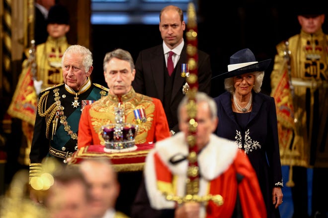 Prince Charles, his wife, Duchess Camilla of Cornwall, and his son Prince William proceed behind the Imperial State Crown for the State Opening of Parliament in the House of Lords on May 10, 2022 in London.