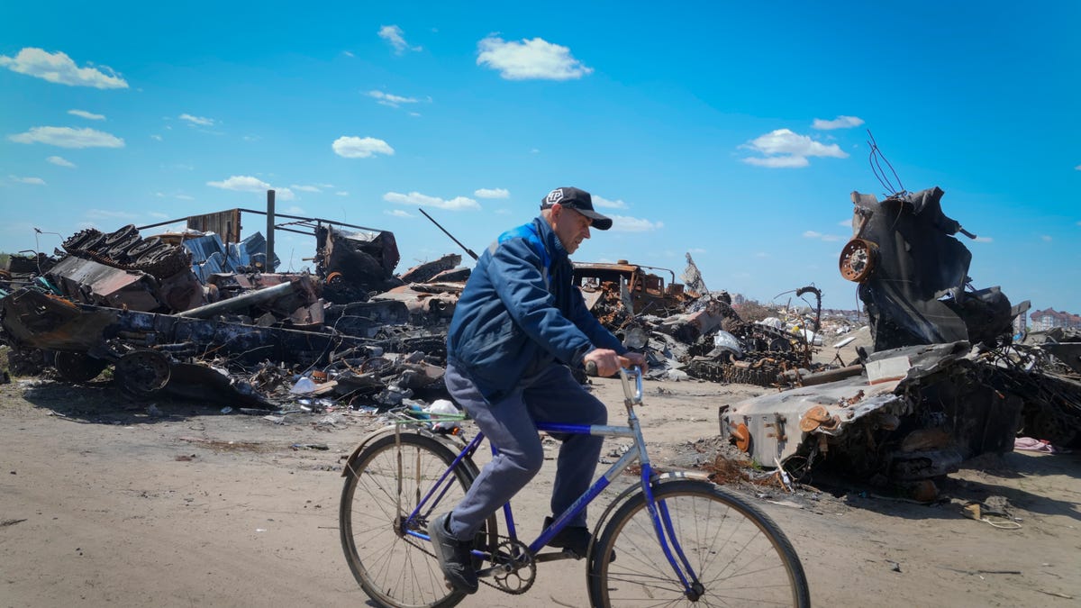 A resident rides a bike past a destroyed Russian military vehicle in Bucha, on the outskirts of Kyiv, Ukraine, on May 10, 2022.