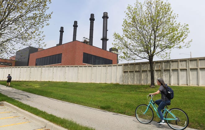 A cyclist passes by the Iowa State University campus power plant on Beach Avenue on Wednesday in Ames.