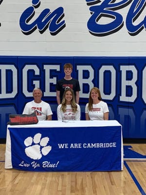 Cambridge High senior Ziciah Gibson, center, sits with her father Tim, left, and mother Tamara, right after signing her Letter of Intent to attend Wittenberg University to run rack next fall. Standing behind in brother Cinjin Gibson.