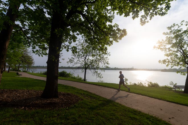 A runner follows the trail around Lake Shawnee on Wednesday morning avoiding the midday heat as record temperatures affect the Topeka area.