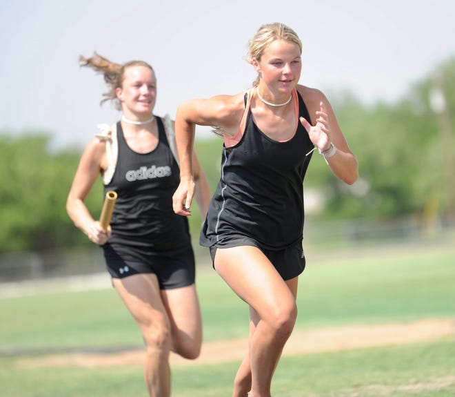 Haskell senior Emma Roewe (right) prepares to receive the baton from Brittany Andrews in mile relay practice on Monday.