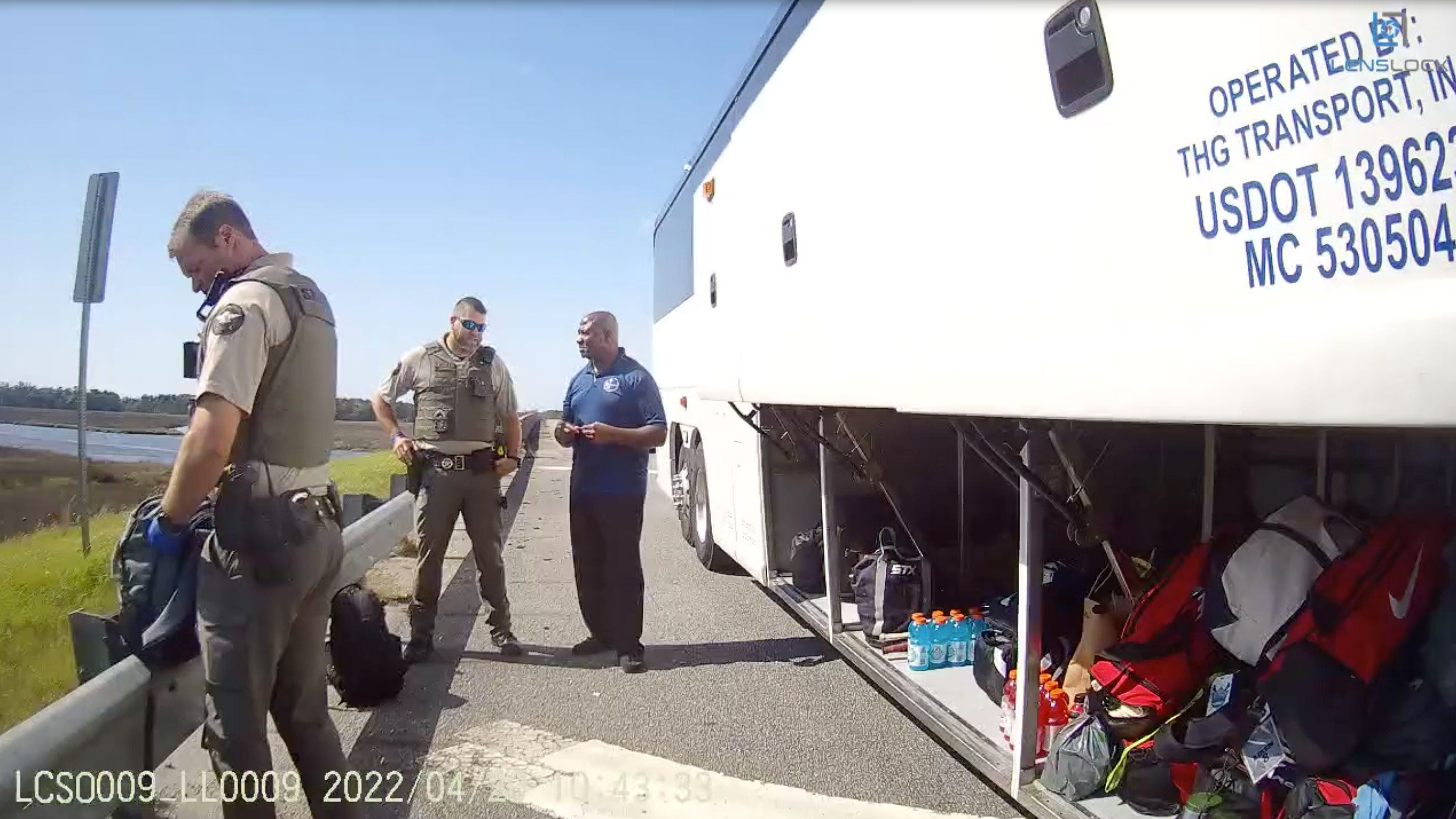 Body camera footage shows Liberty County deputies beginning their search of luggage belonging to the Delaware State University women's lacrosse team during a traffic stop on April 20, 2022, in Georgia.  The team's bus driver (middle) talks to one of the officers.