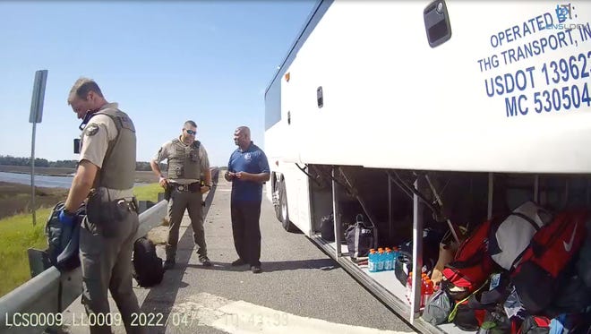 Body camera footage shows Liberty County deputies beginning their search of luggage belonging to the Delaware State University women's lacrosse team during a traffic stop on April 20, 2022, in Georgia. The team's bus driver (middle) talks to one of the officers.