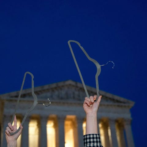 Pro-choice demonstrators hold coat hangers, a symb