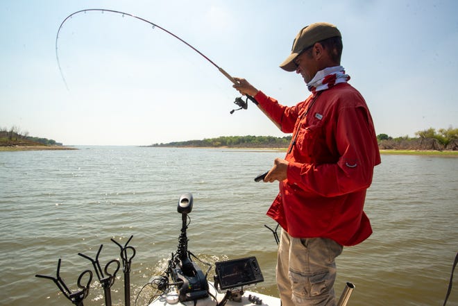 Fishing guide Joe Bragg has one hand on his live sonar remote while using the other to reel in a crappie Tuesday at Milford Lake. Shortly after pinpointing a fish on his sonar, Bragg was able to drop his line right in front of it, increasing the odds of a bite.