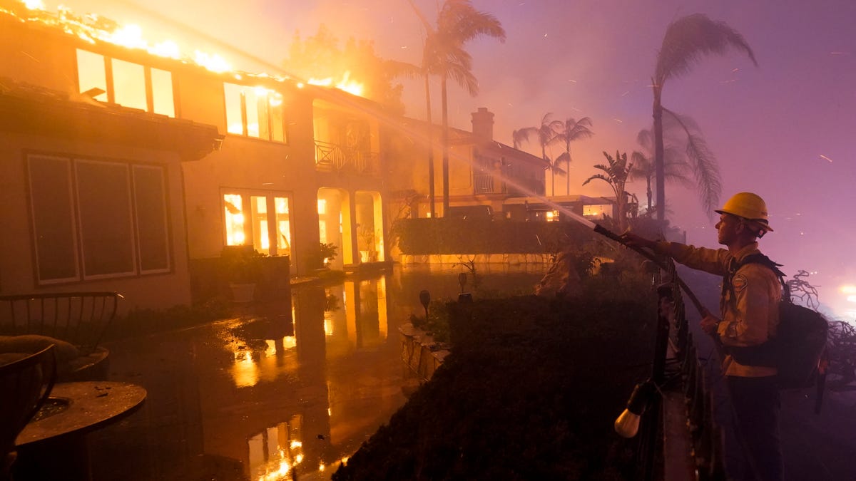 A firefighter works to put out a structure burning during a wildfire May 11 in Laguna Niguel, Calif.